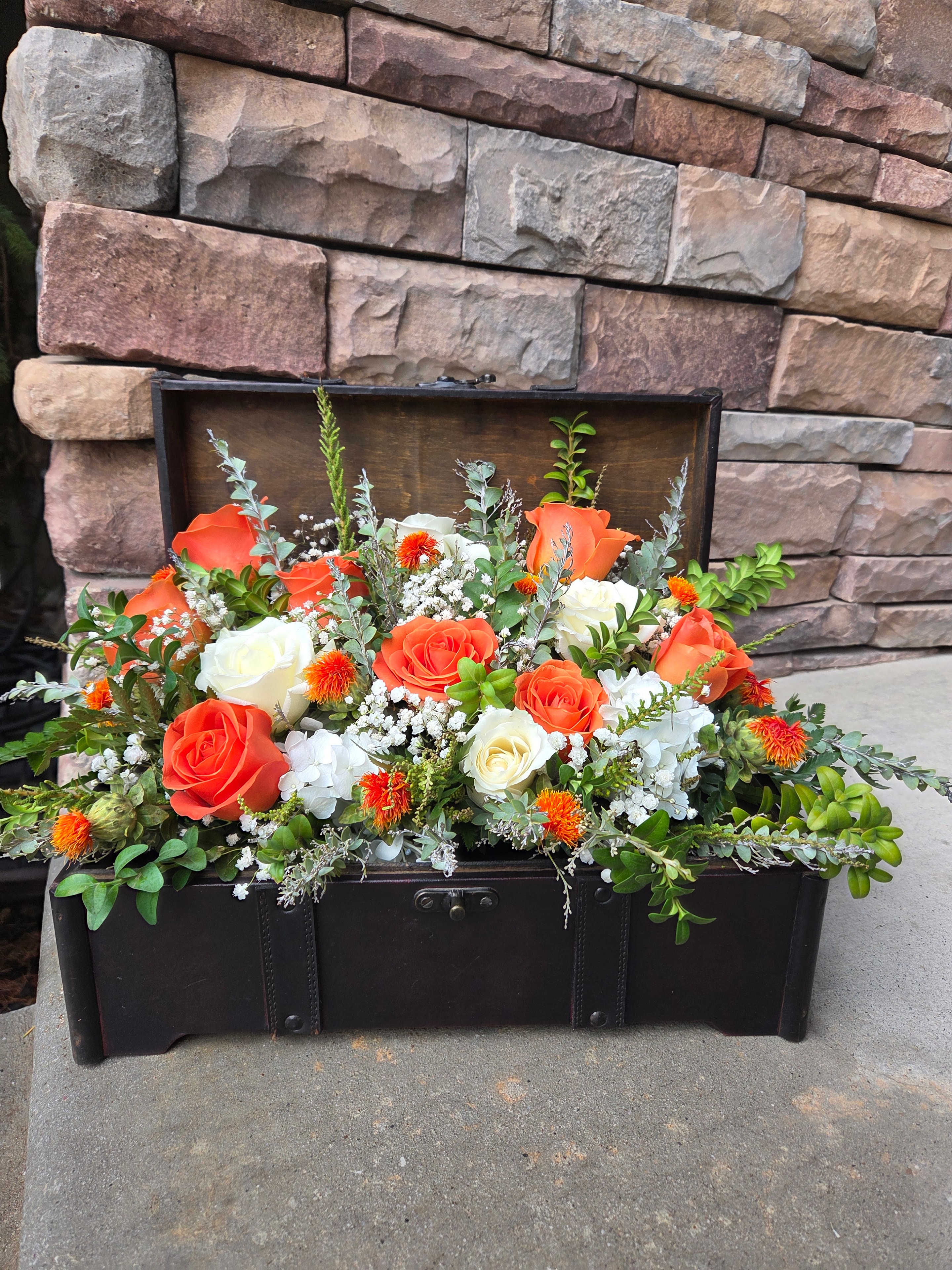 Coral and white floral arrangement with roses and greenery.