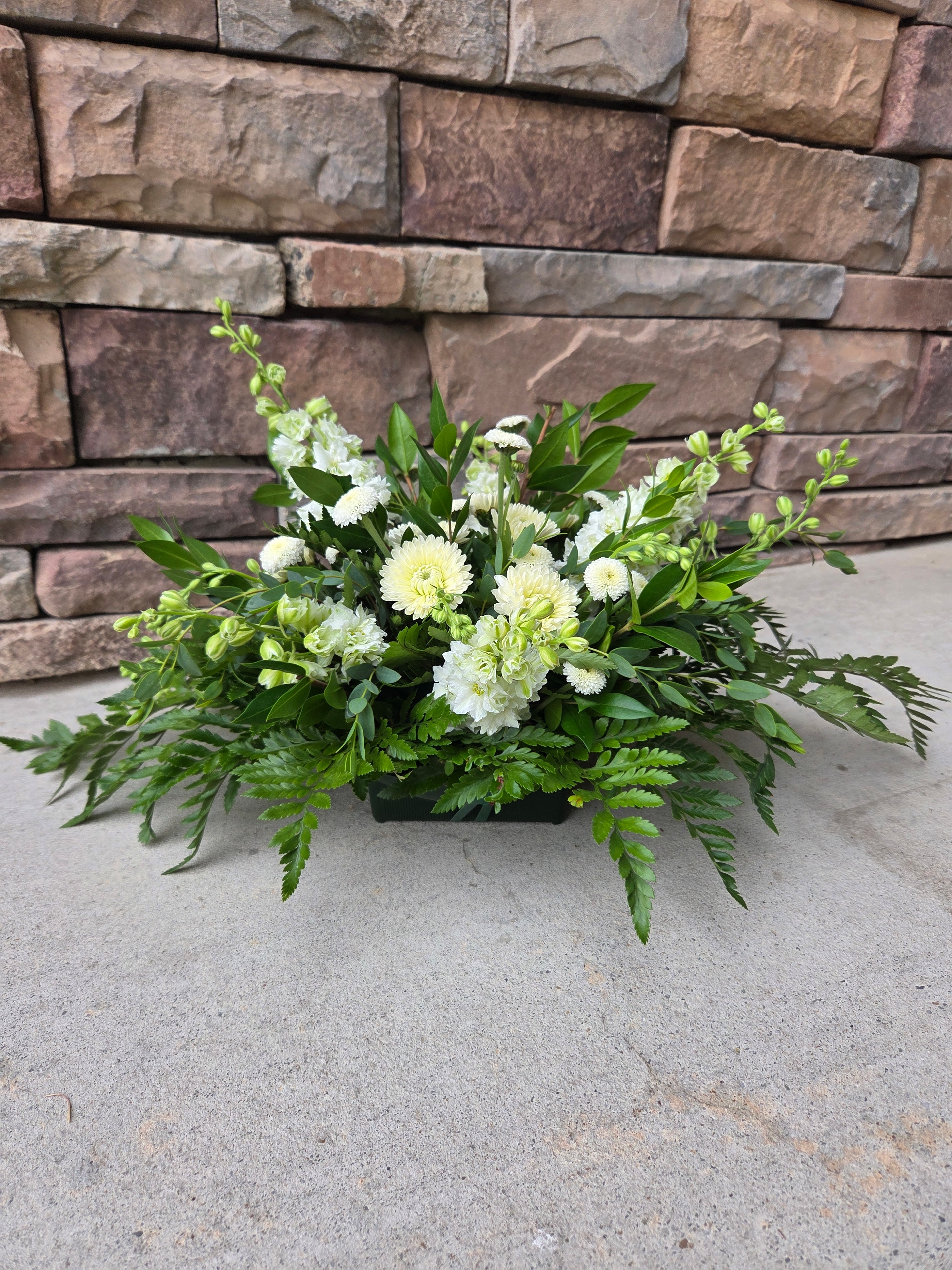 White and pale green floral arrangement with lush greenery.